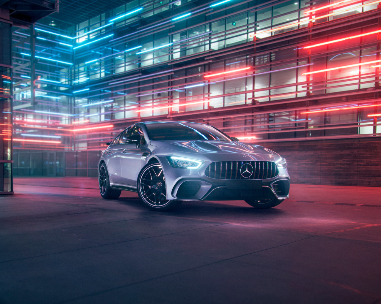 Серебристый автомобиль Mercedes AMG GT4 на фоне здания