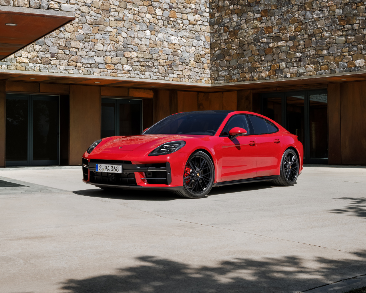 Красный автомобиль Porsche Panamera GTS 2024 года у здания