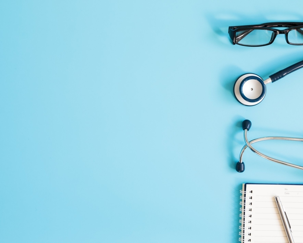 Стетоскоп, очки и блокнот на голубом фоне