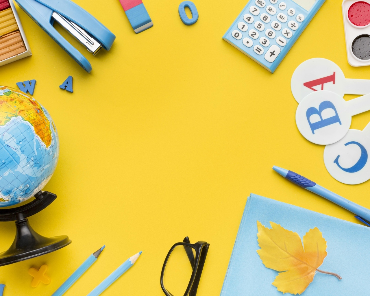 Красивые канцелярские предметы и глобус на желтом фоне