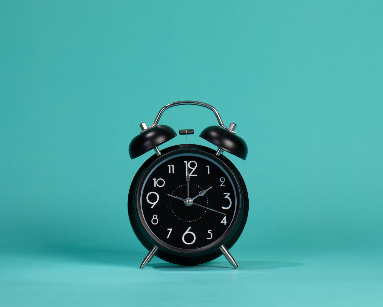Черный будильник на голубом фоне