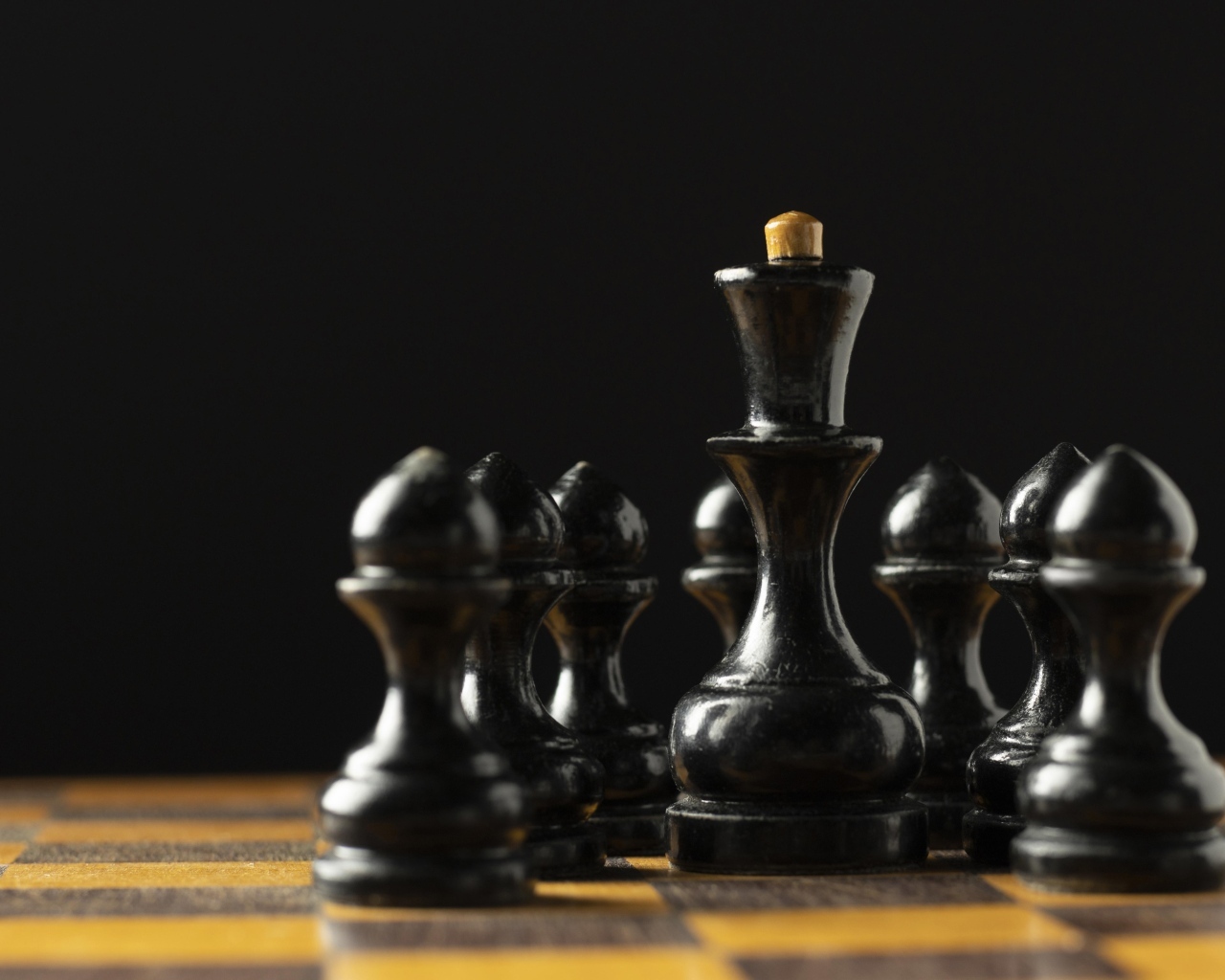Черные шахматные фигуры на доске на черном фоне