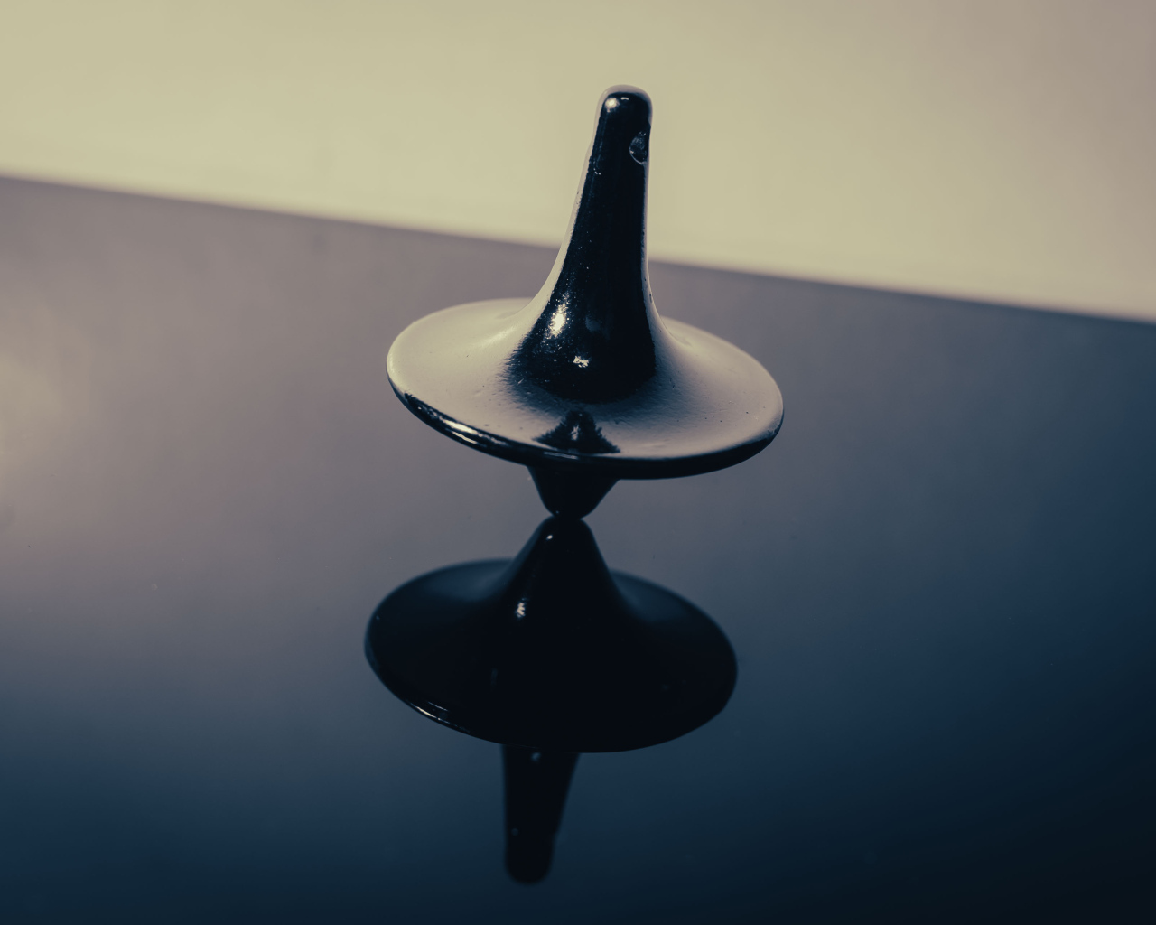 Черный волчок на ровной поверхности