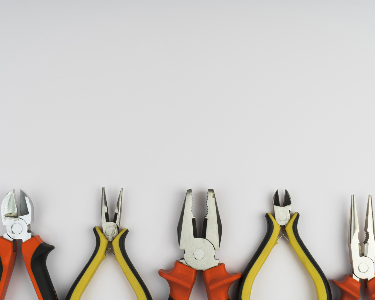 Разные плоскогубцы на сером фоне