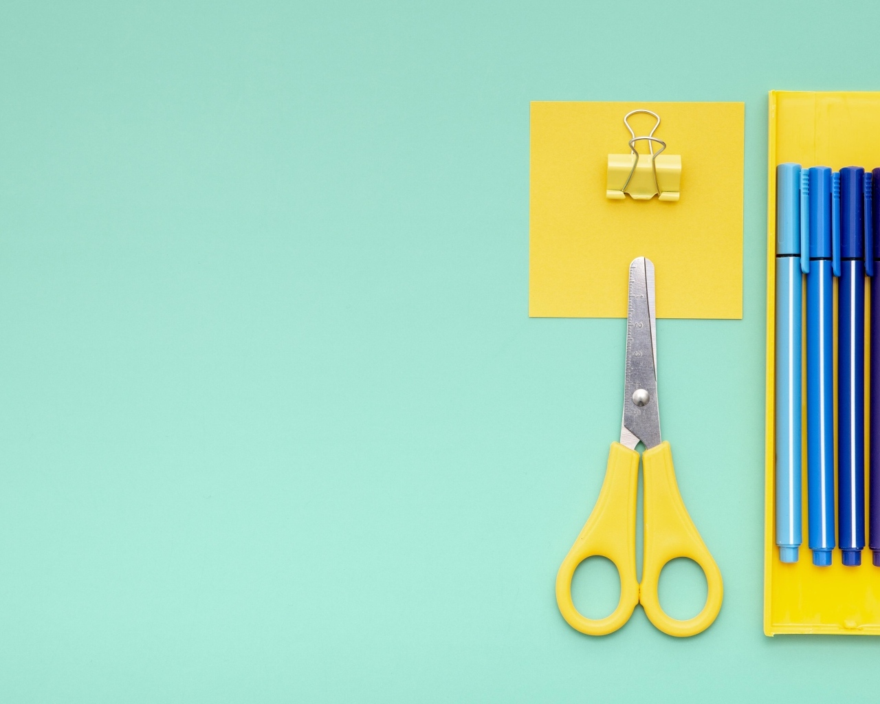 Фломастеры, ножницы и карандаш на голубом фоне