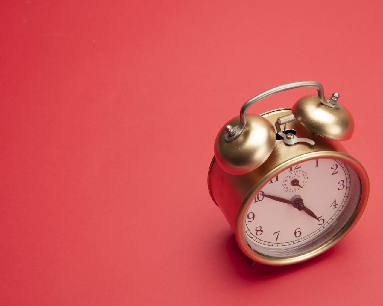 Золотой будильник на красном фоне