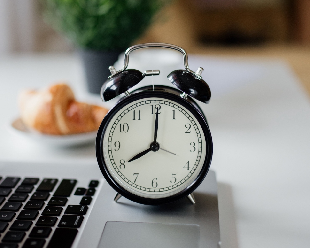 Большой черный будильник на столе у ноутбука