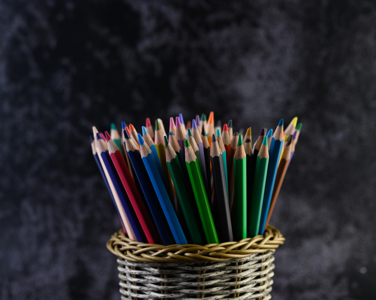 Разноцветные карандаши в стакане на сером фоне