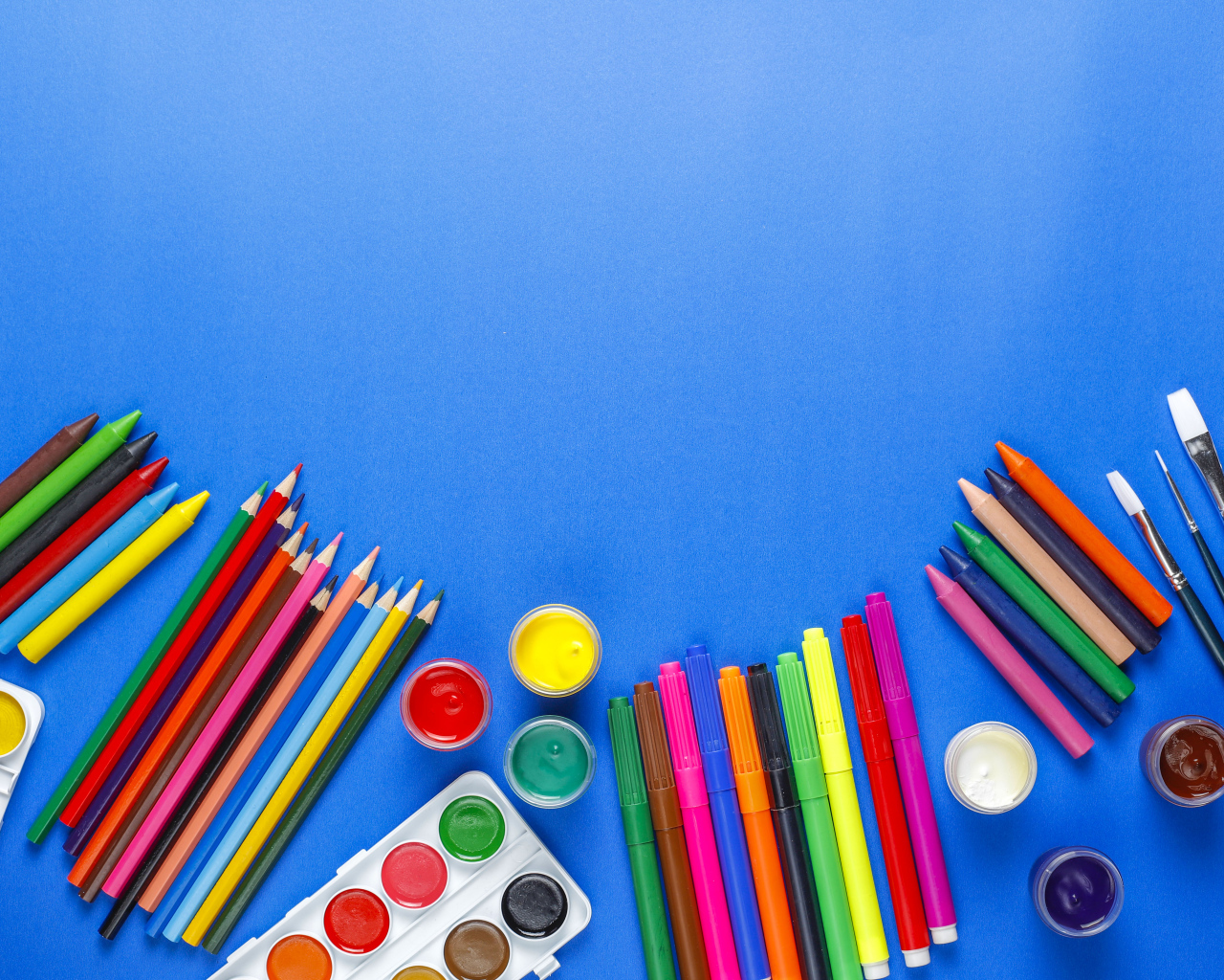 Карандаши, краски, фломастеры и кисти на голубом фоне