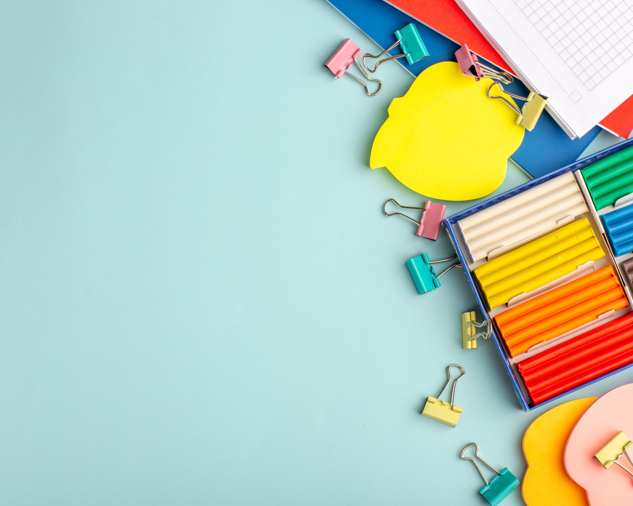 Пластилин на голубом фоне со скрепками и блокнотами