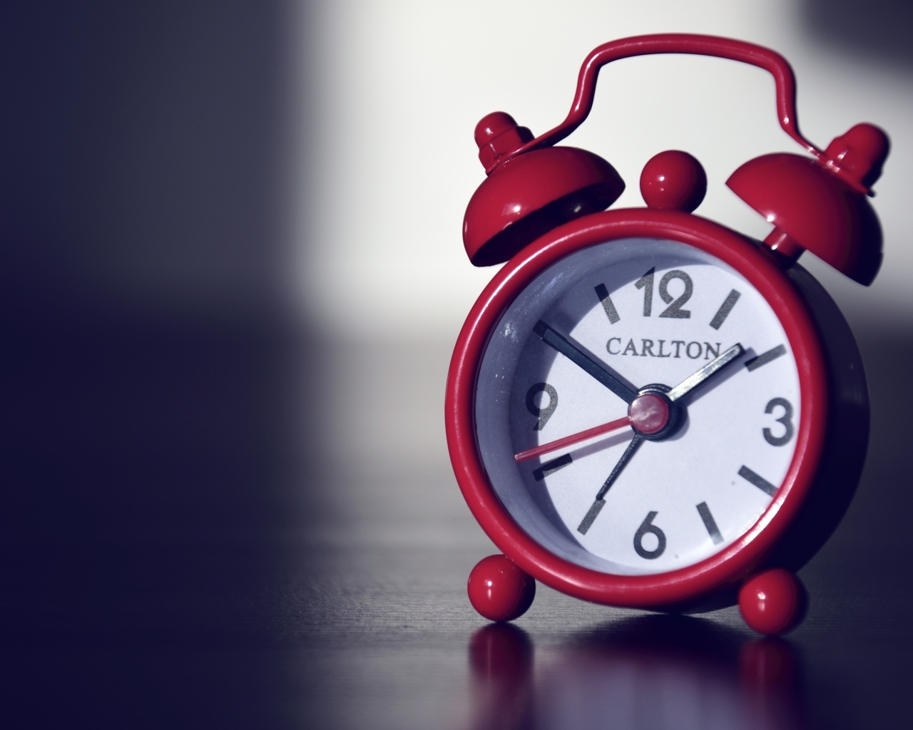 Красный будильник на черном столе