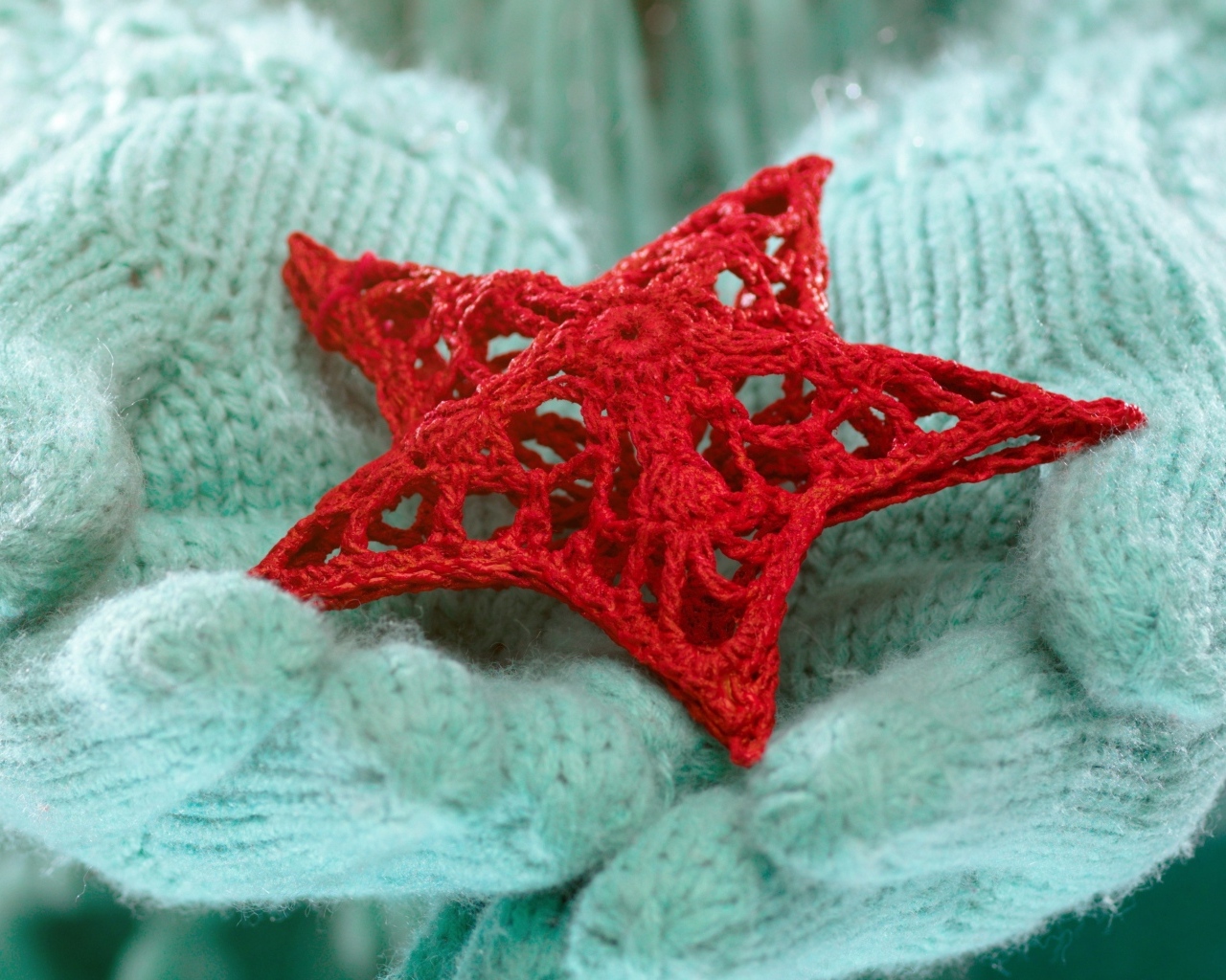 Красная вязаная звезда в руках в варежках