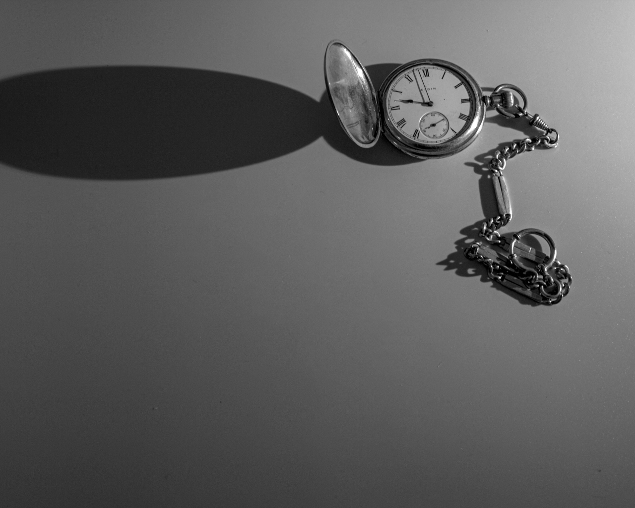 Тень от карманных часов на сером фоне