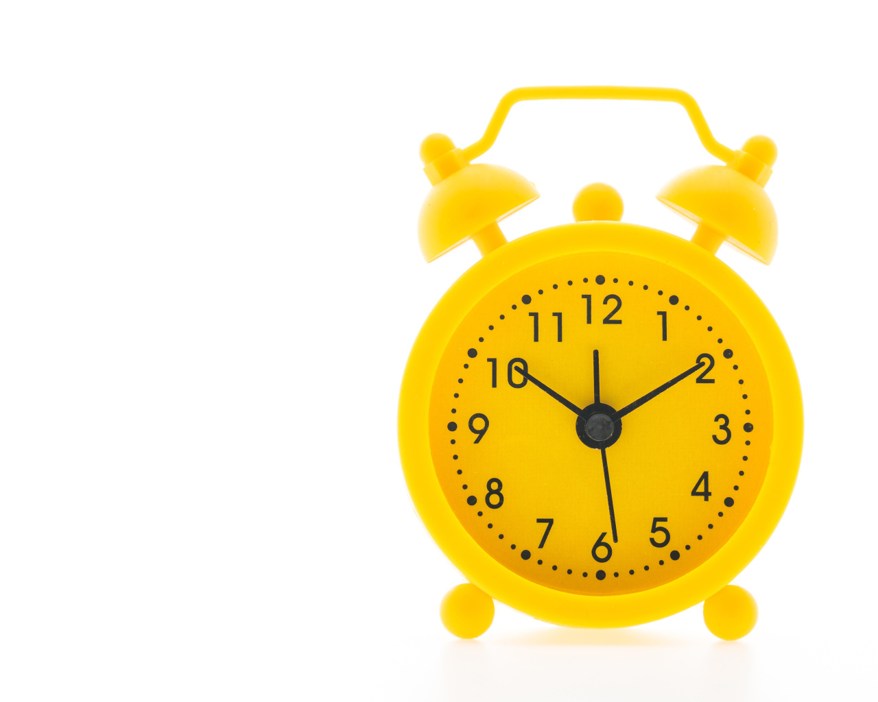 Желтый будильник на белом фоне