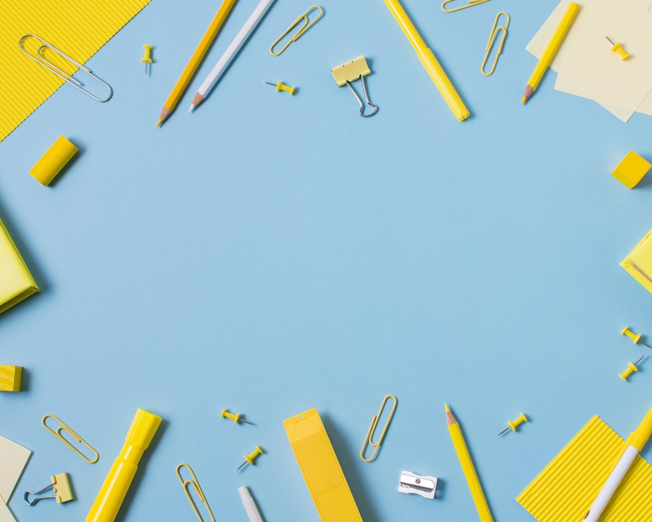 Желтые канцелярские предметы на голубом столе