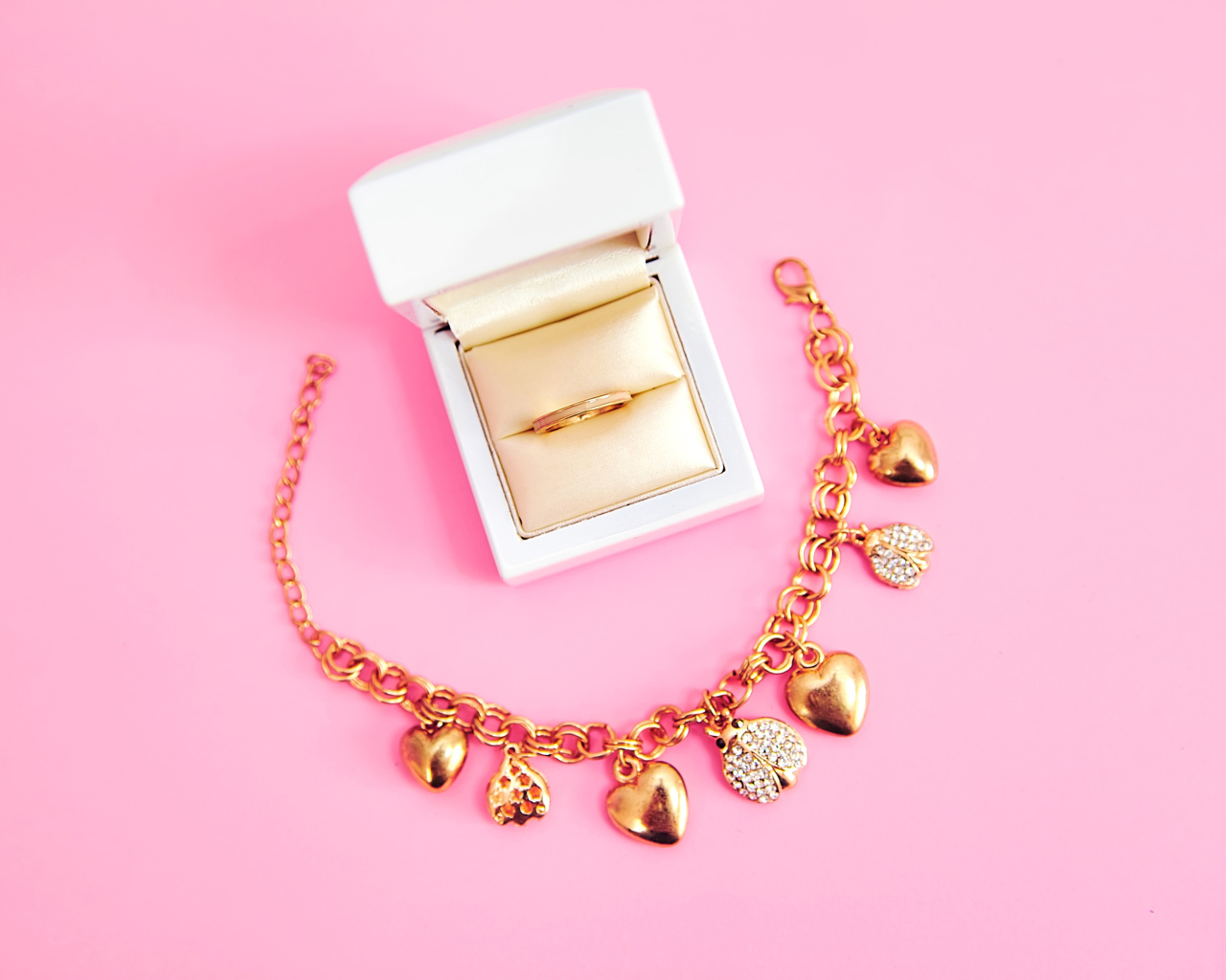Браслет и кольцо в коробке на розовом фоне
