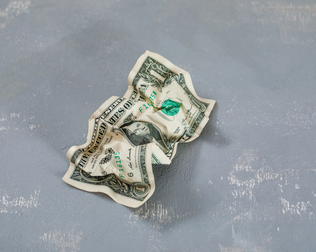 Смятая купюра один доллар на сером столе