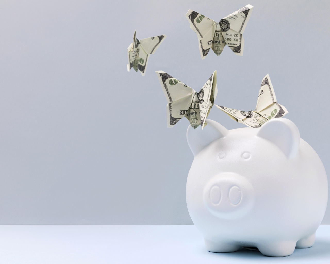 Свинья копилка с бабочками из купюр на сером фоне