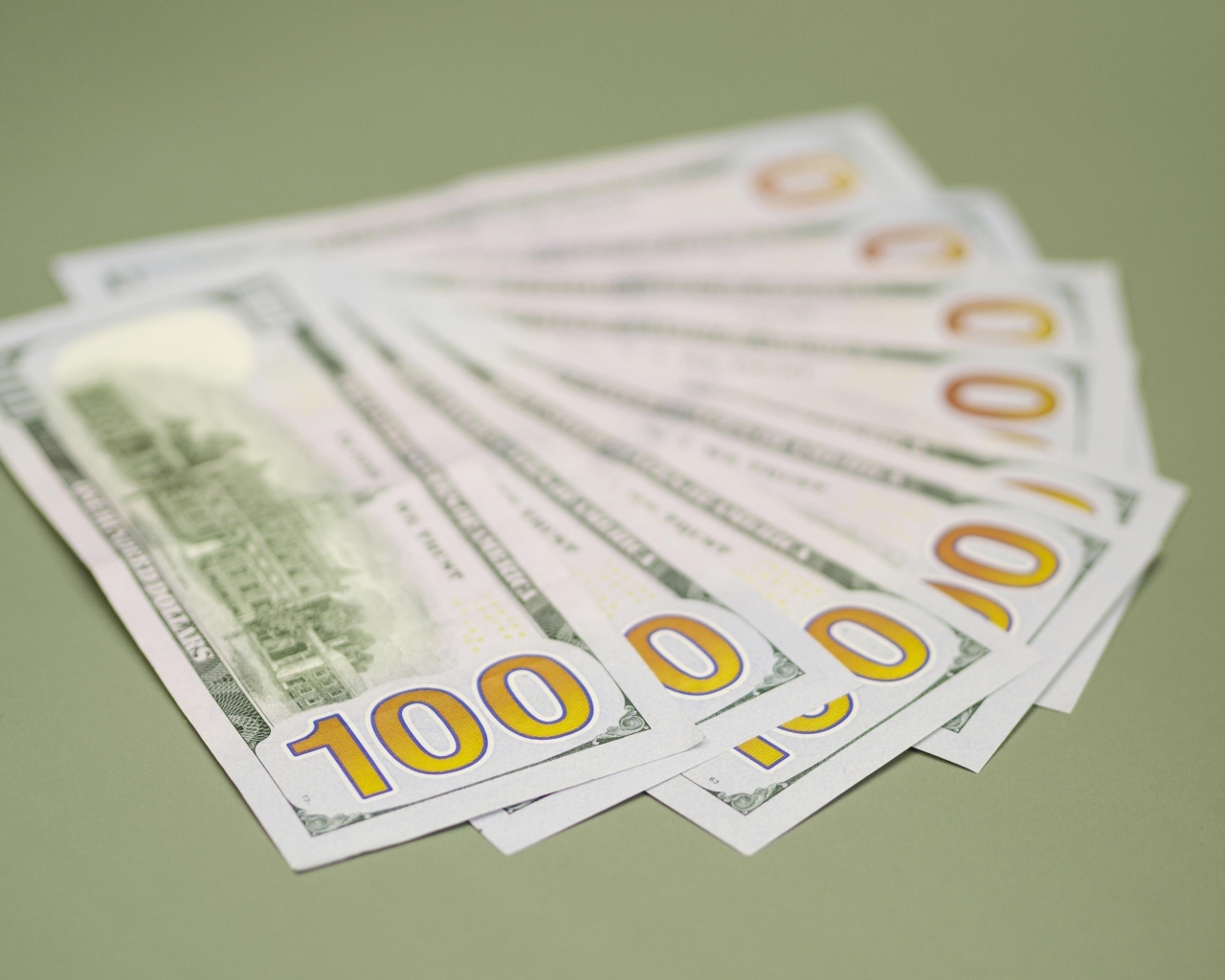 Пачка стодолларовых купюр на зеленом фоне