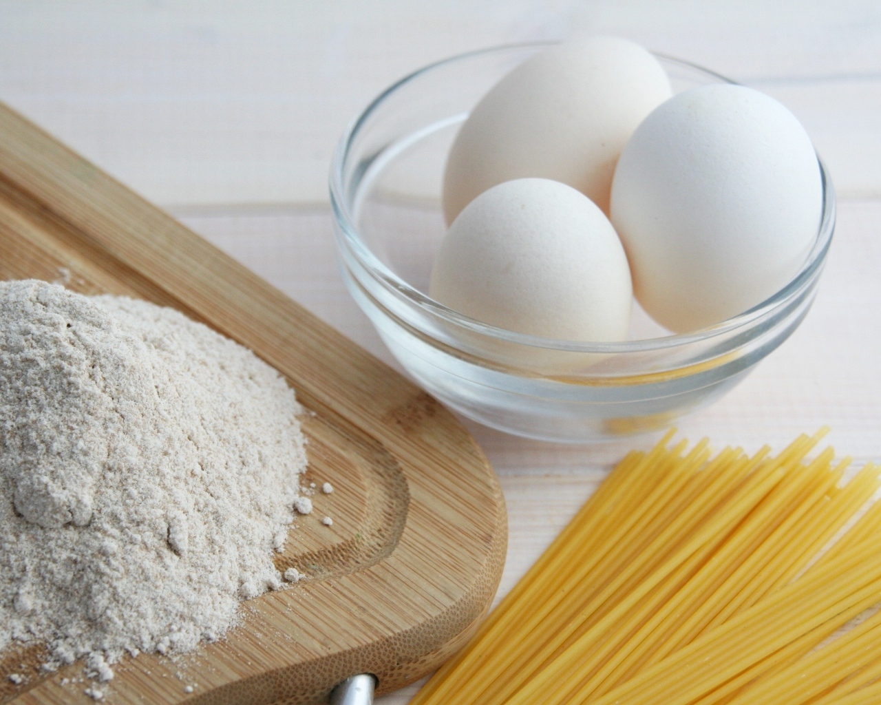 Яйца на столе с мукой и спагетти
