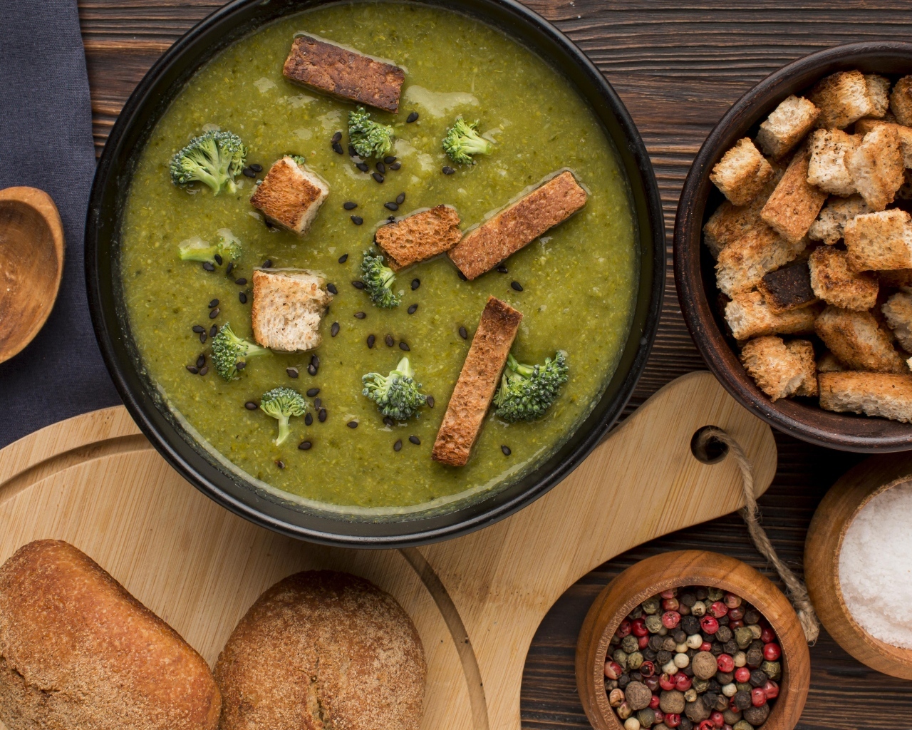 Зеленый суп пюре на столе с сухариками и перцем