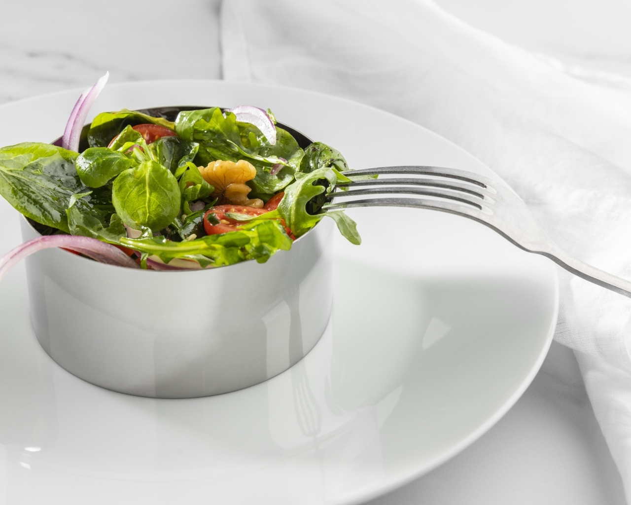 Зеленый салат с орехами на большой белой тарелке