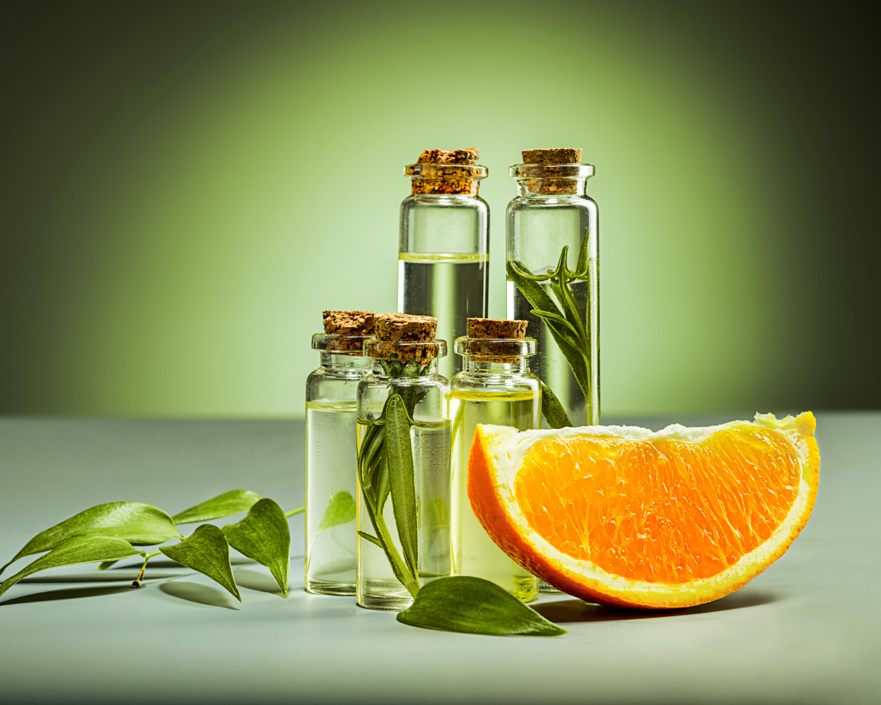 Апельсиновое масло на зеленом фоне с апельсинами