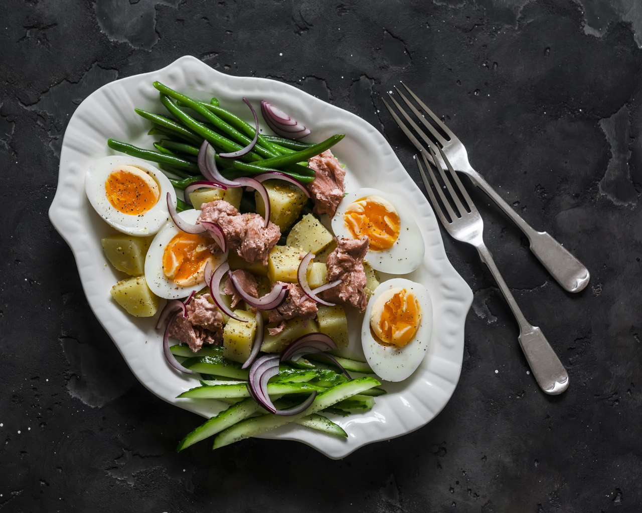 Картофель с мясом, яйцами, спаржей и огурцами на тарелке