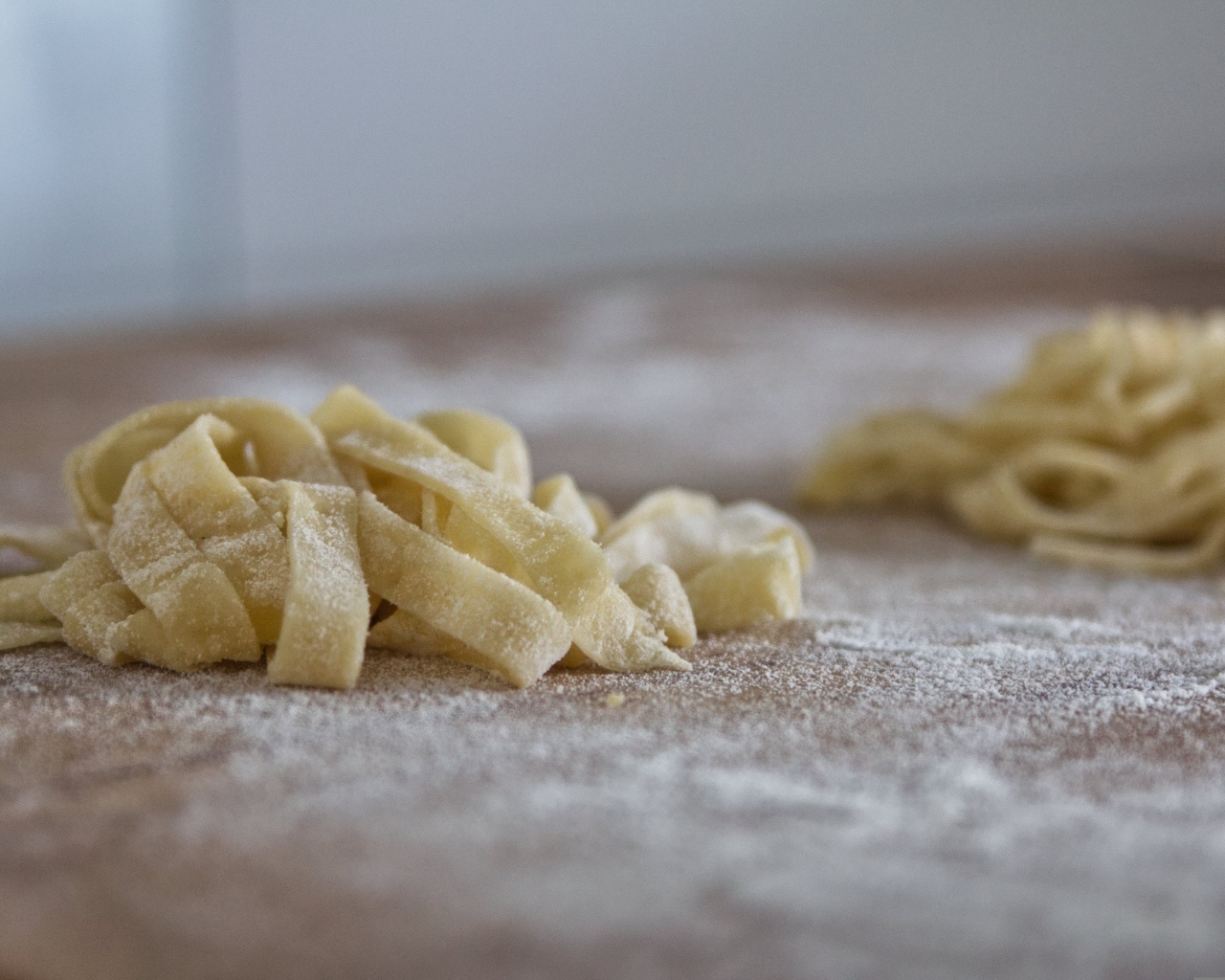 Сырое тесто для лапши на покрытом мукой столе