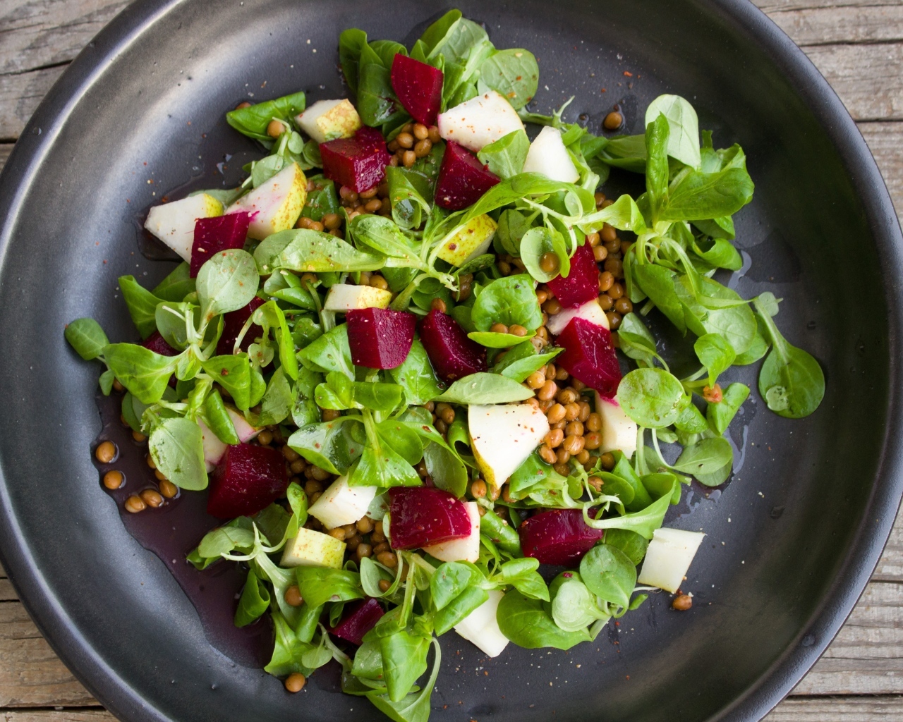 Салат с зеленью в большой черной тарелке