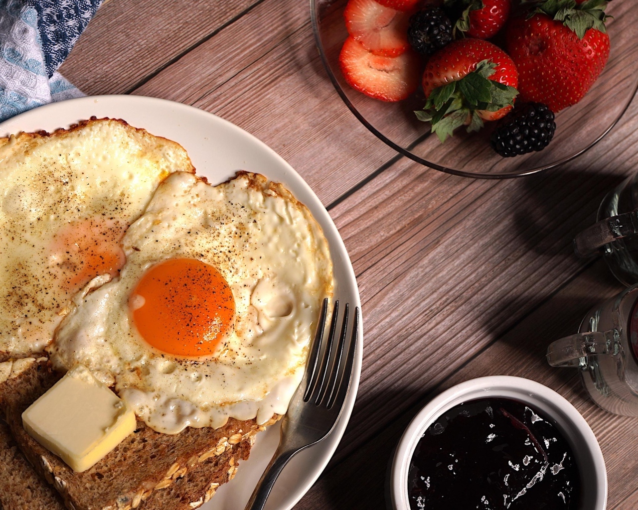 Яичница с гренками на столе с клубникой