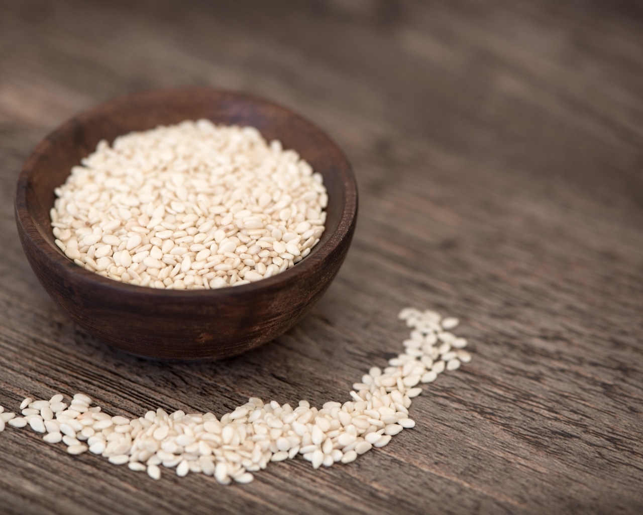 Зерна кунжута в деревянной миске на столе
