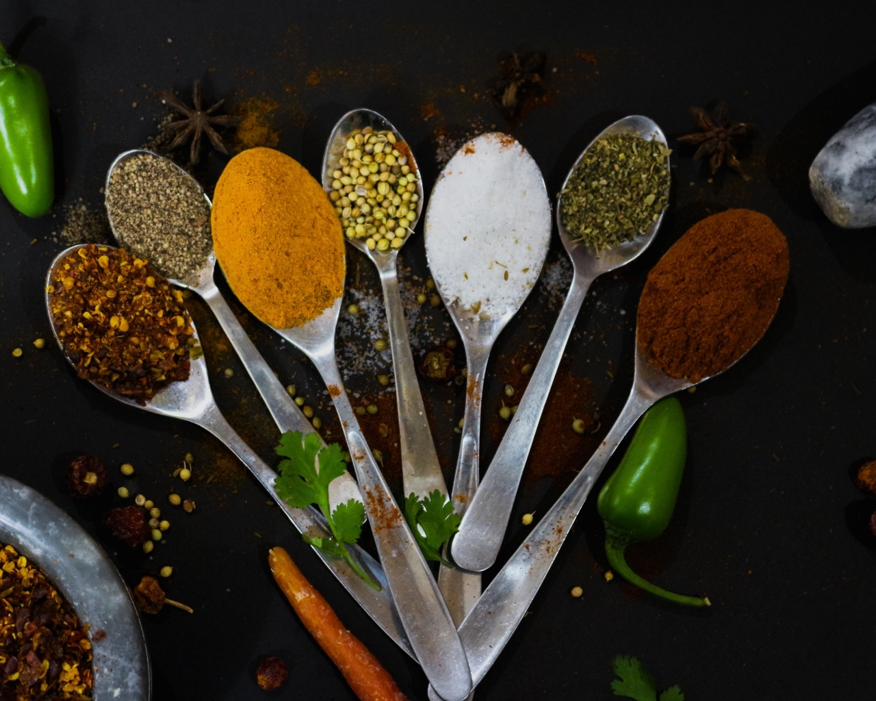 Ложки с ароматными специями на черном столе