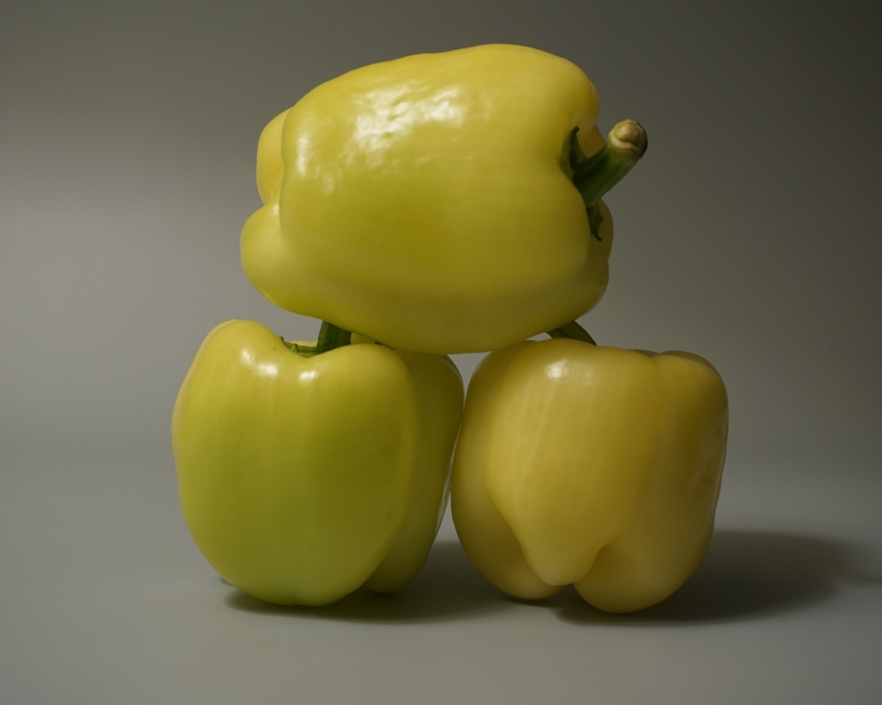 Три желтых перца на сером фоне