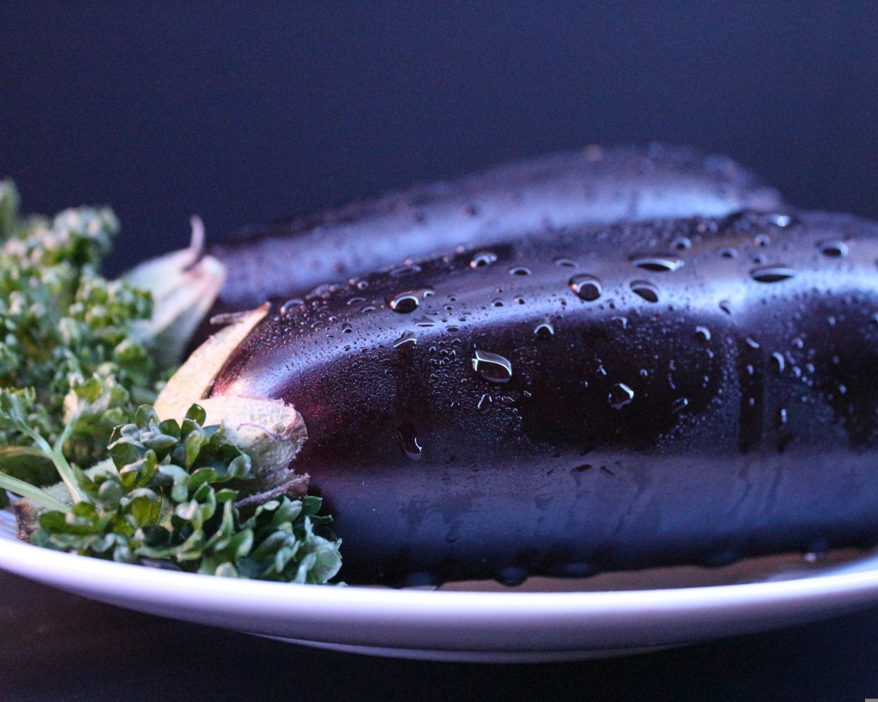 Два баклажана на тарелке с зеленью