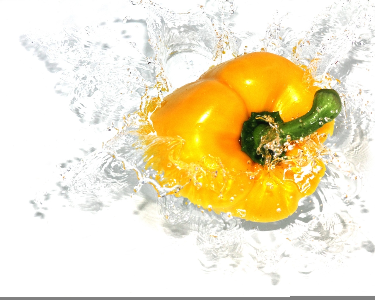 Желтый сладкий перец в воде на белом фоне