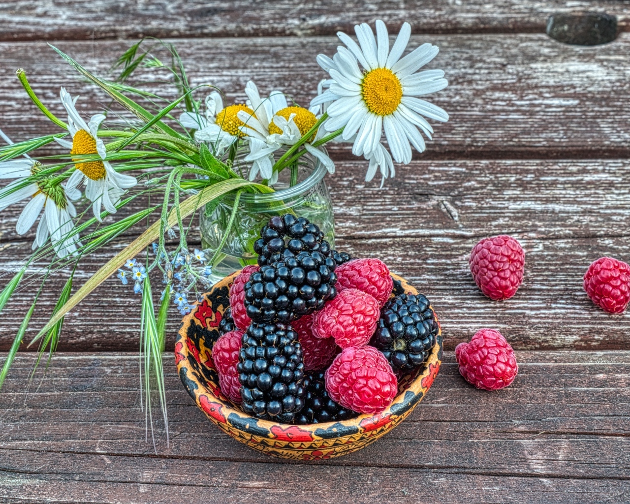 Ягоды черники и малины на столе с ромашками