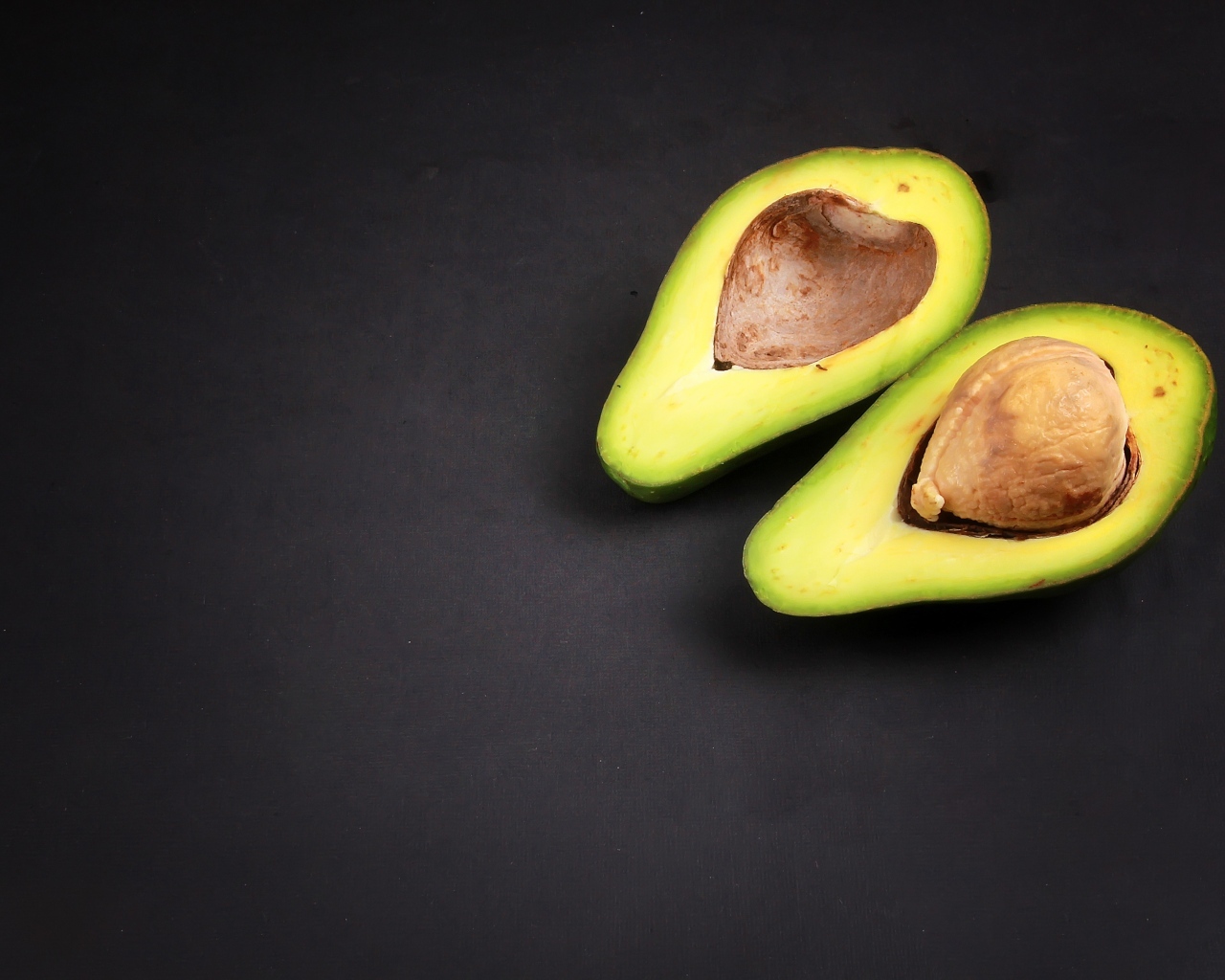 Свежий зеленый авокадо на черном фоне