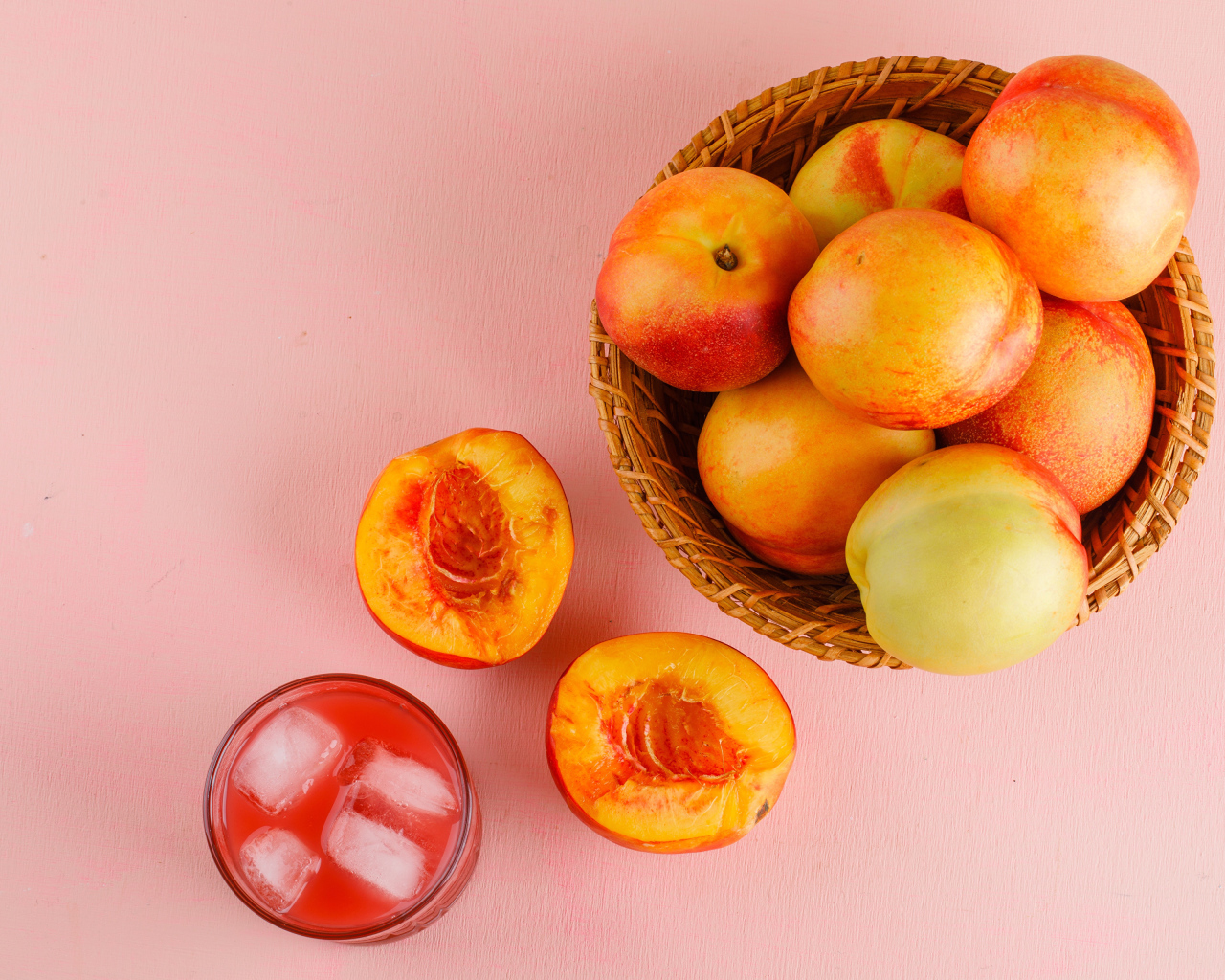 Свежий нектарин в корзине на розовом столе