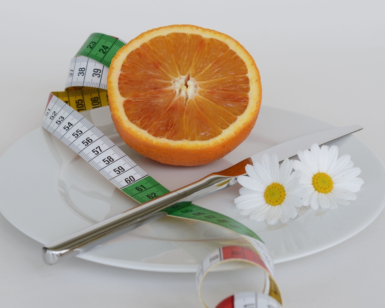 Половина апельсина на тарелке с сантиметром