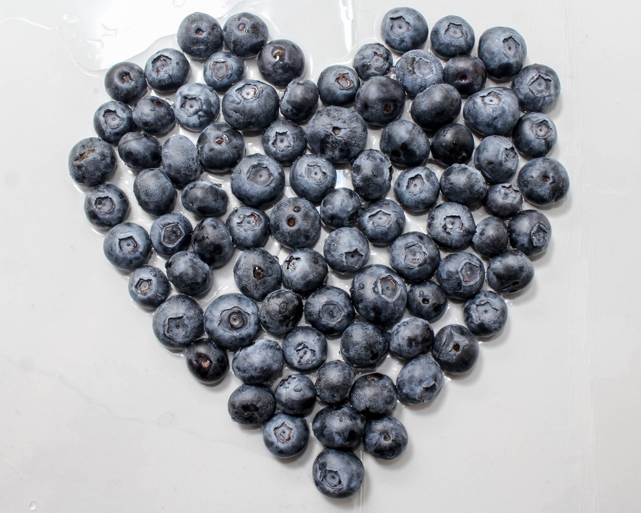 Сердце из ягод черники на сером столе