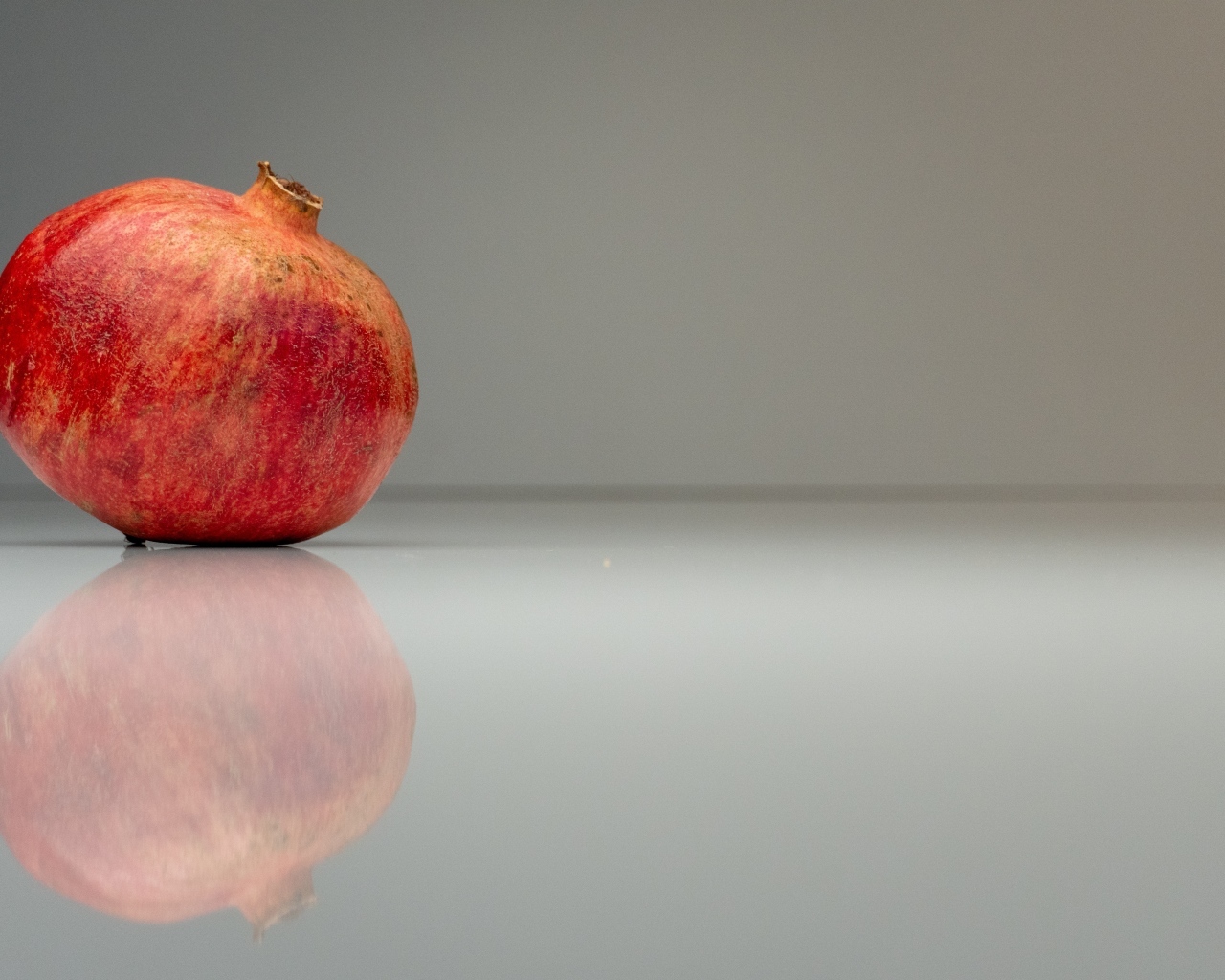 Красный гранат отражается в серой зеркальной поверхности