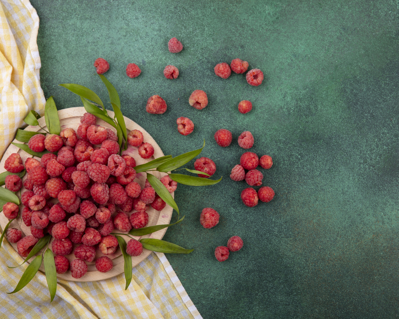 Красная малина с зеленой листвой на столе