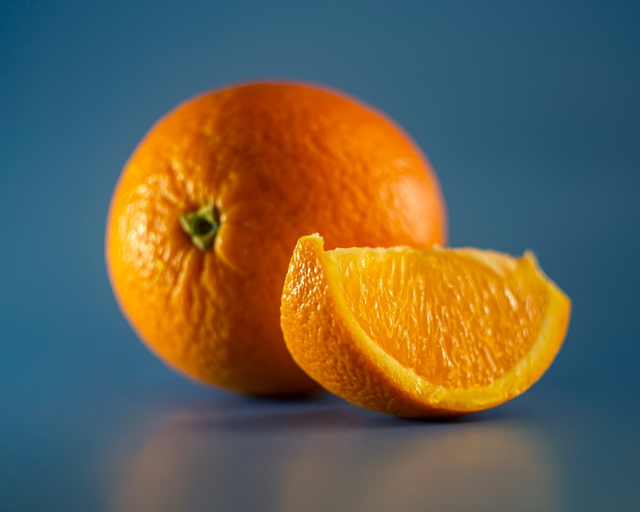 Спелый оранжевый апельсин на голубом фоне