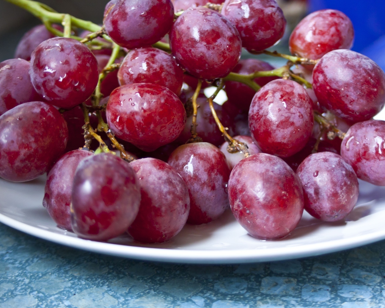 Спелый розовый виноград на белой тарелке