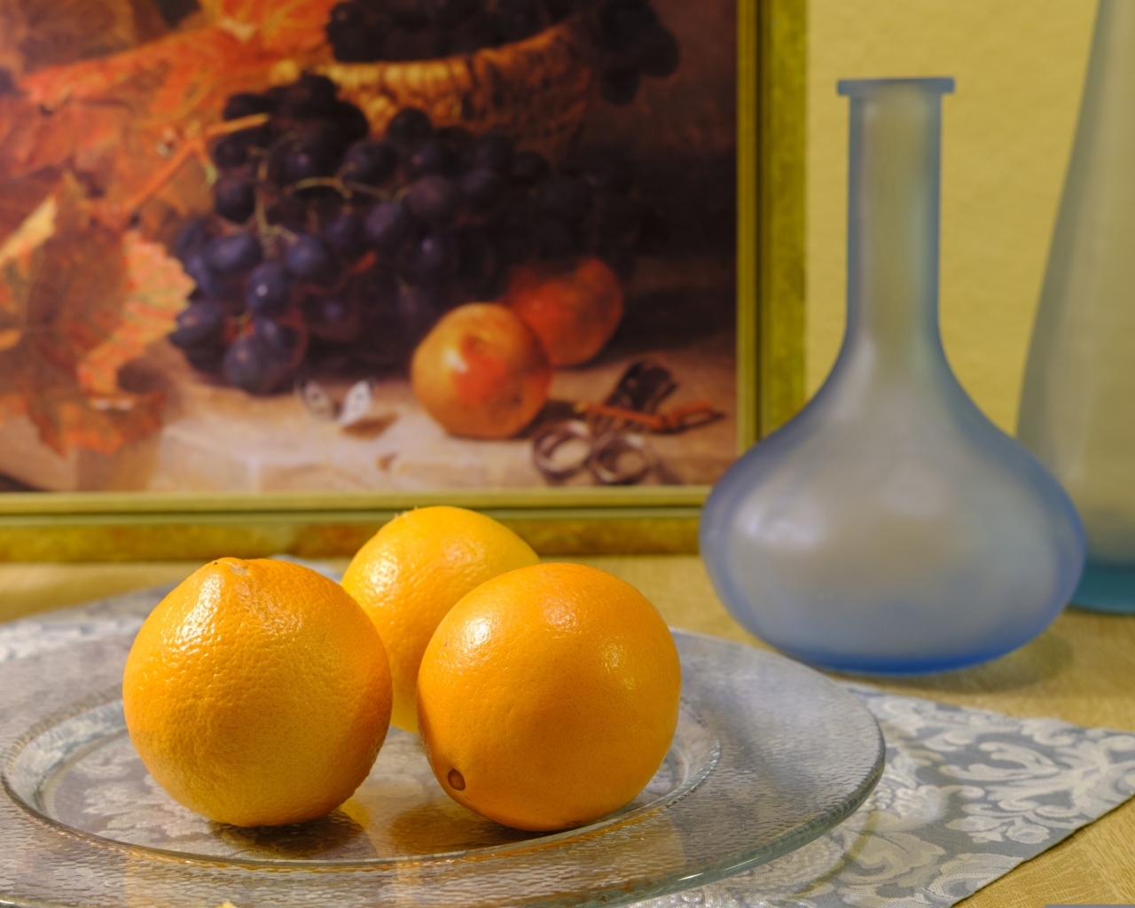 Три апельсина с вазами на столе