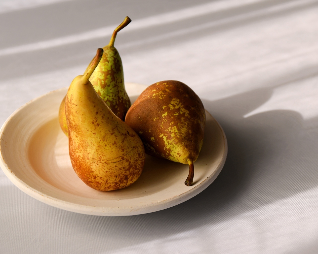Три груши на тарелке на столе