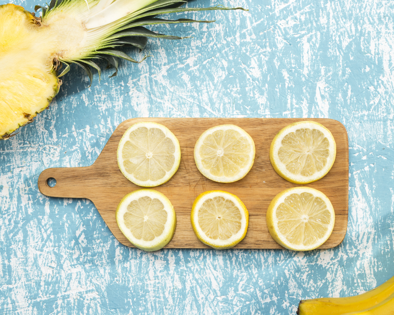 Деревянная доска с лимоном на столе с ананасом