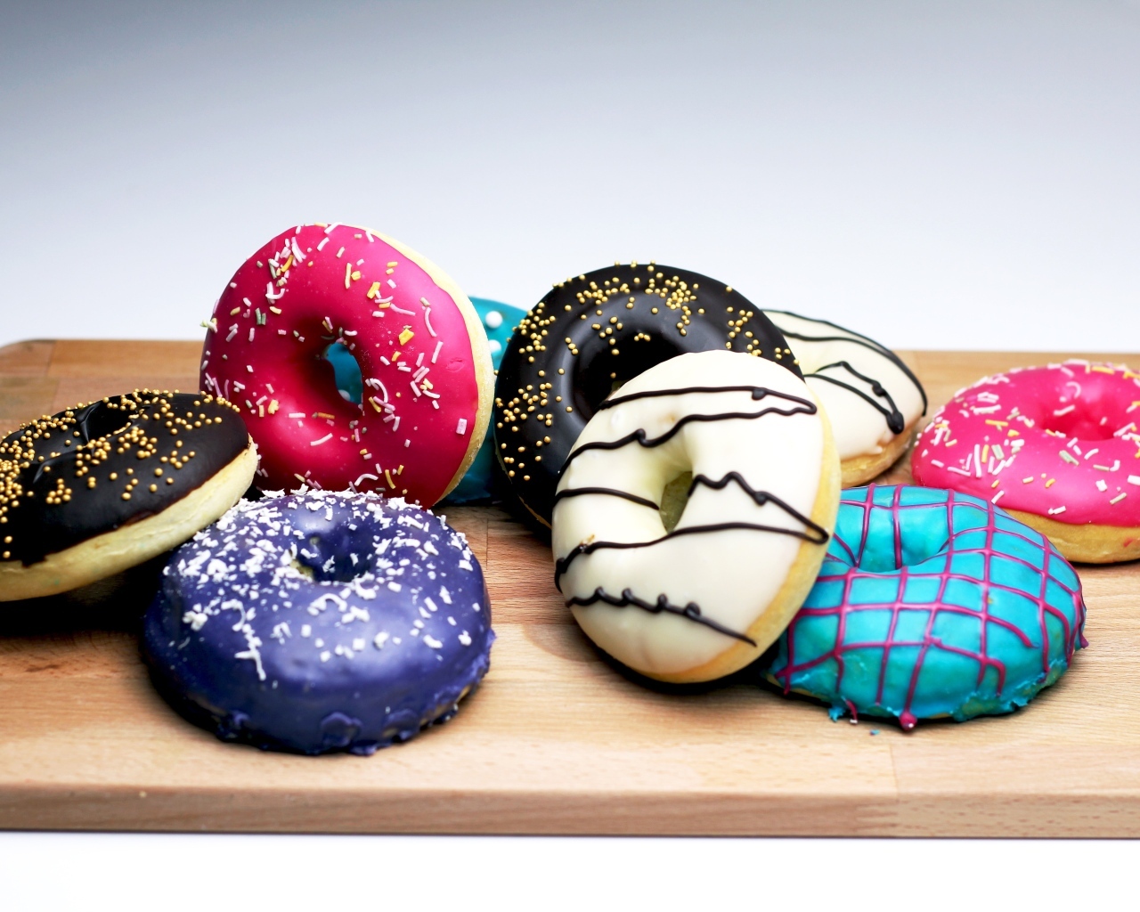 Аппетитные разноцветные пончики на деревянной доске