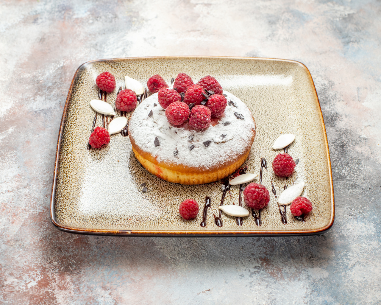 Пирожное с сахарной пудрой и малиной на тарелке